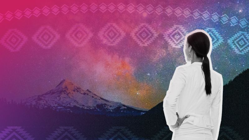 An Indigenous woman in a white suit looks at a starry night sky.