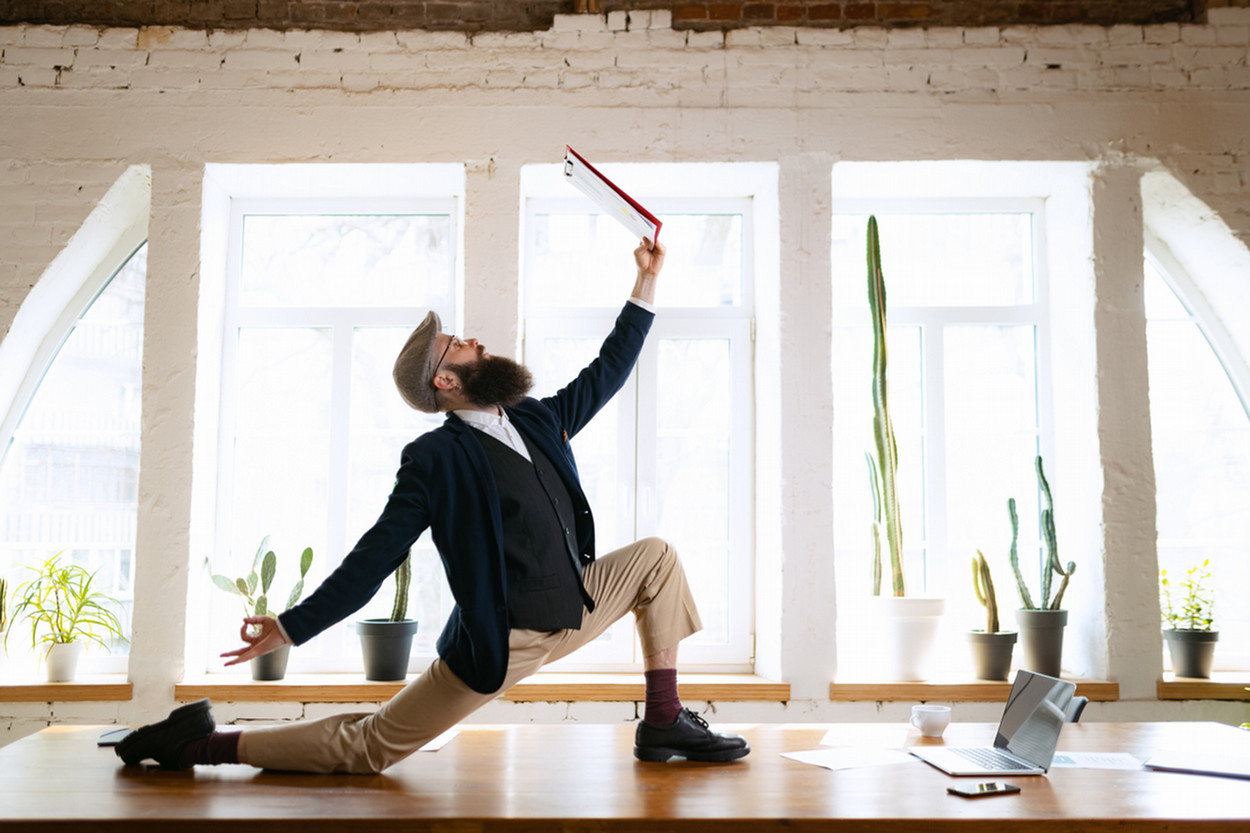 Young bearded man doing a deep lunge on an office desk