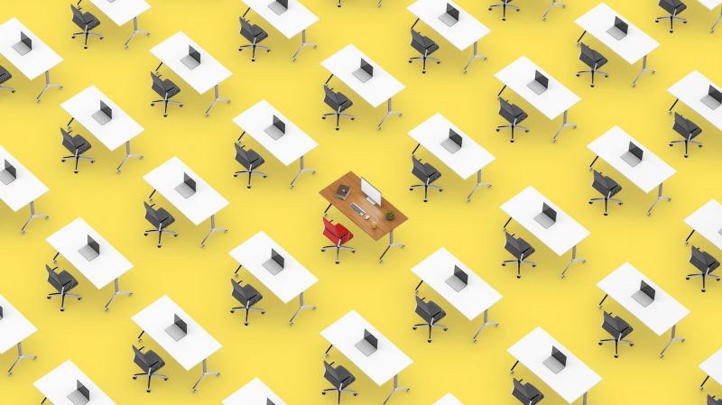 Rows of identical office desks, with one unique desk in the middle of the room.