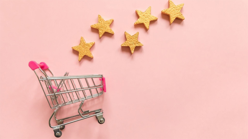 Small shopping card and 5 gold stars rating isolated on pink pastel background