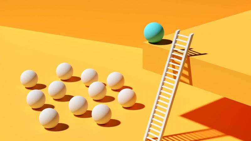 A blue ball on a high ledge with a ladder overlooking a group of white balls 