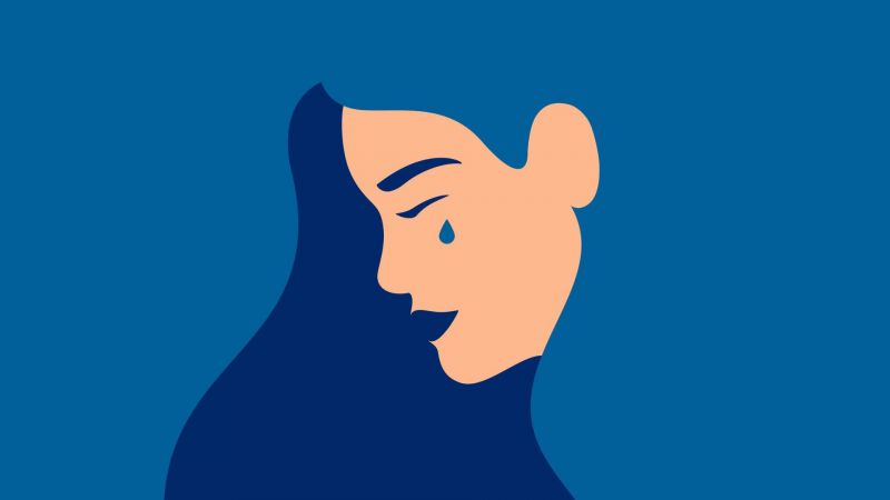 Side view of a tearful woman on blue background