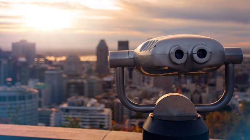 Observation deck binoculars with view of Montreal at sunset.