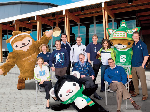 QSB alumni on the VANOC Team in their 2010 apparel, from left: Leah Walton, Mary Thomson, Benjy Berger, Chris Gear, Dick Vollet, John McLaughlin (seated) Don Ford, Katrina Galas, Mike Wilkinson (seated) and Shane Holland, with Olympic mascots Quatchi (far left), Sumi (right) and Miga (front).